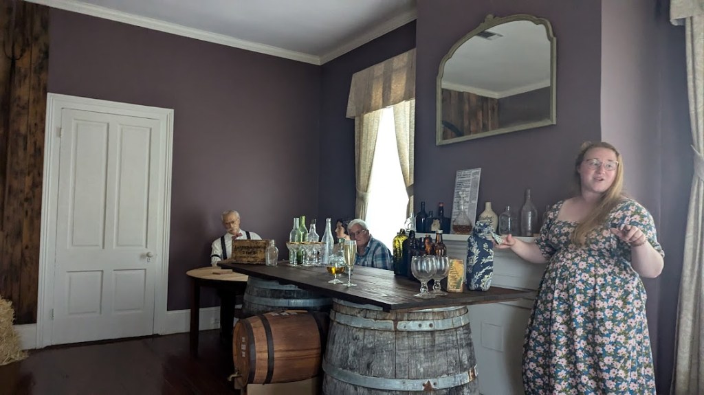 Interior of a room decorated to appear to be a bar: a young woman is lecturing