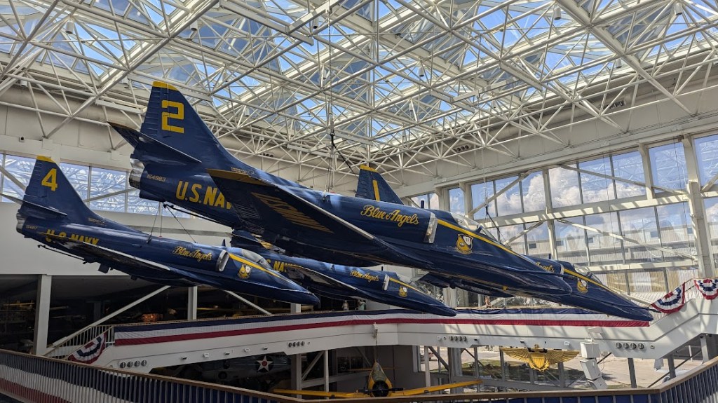 Three blue jets suspended from a ceiling, seen at eye level from a balcony 
