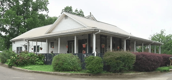 A home-turned-bookstore and cafe, featuring a wraparound portch and bushes