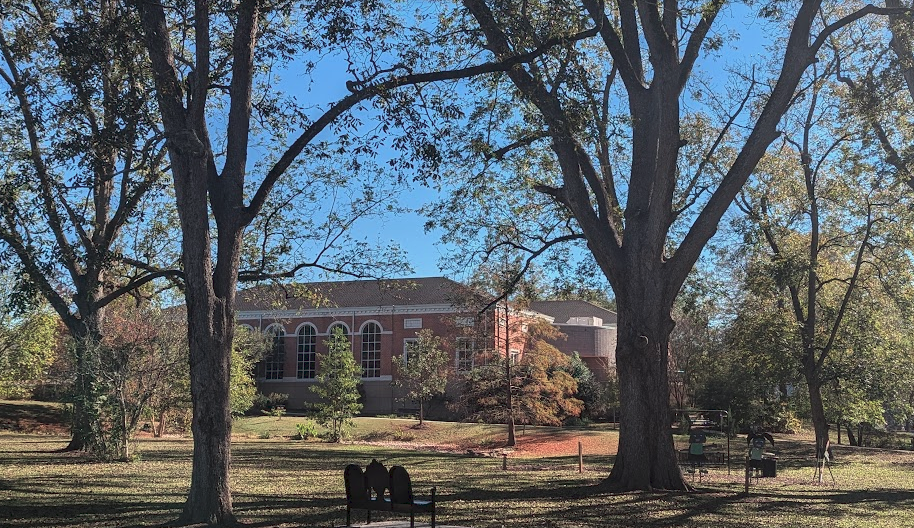 A small brick library surrounded by a park with benches
