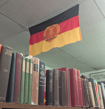 A case of old books with an East Germany flag above it 