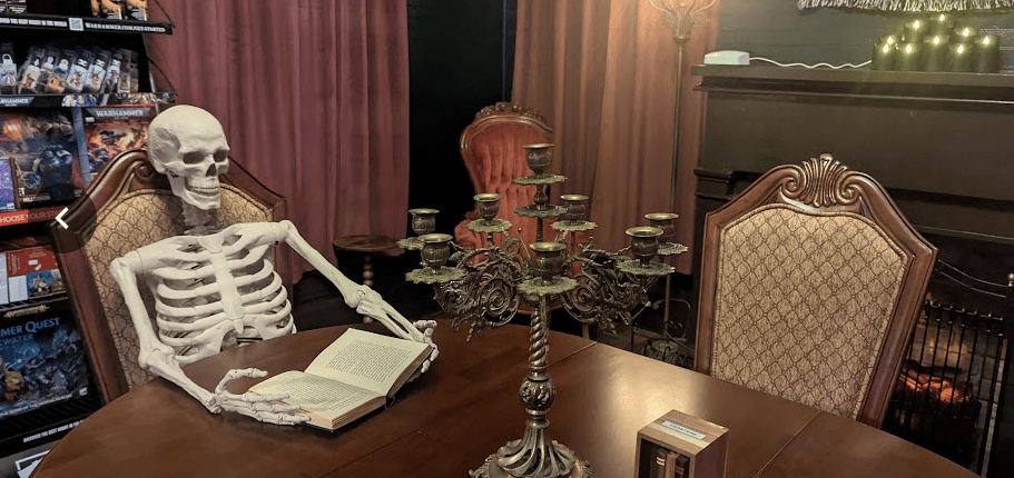 A skeleton sitting at a table reading a book
